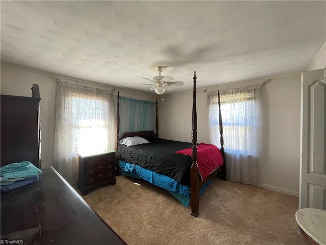 carpeted bedroom with a textured ceiling, multiple windows, and a ceiling fan