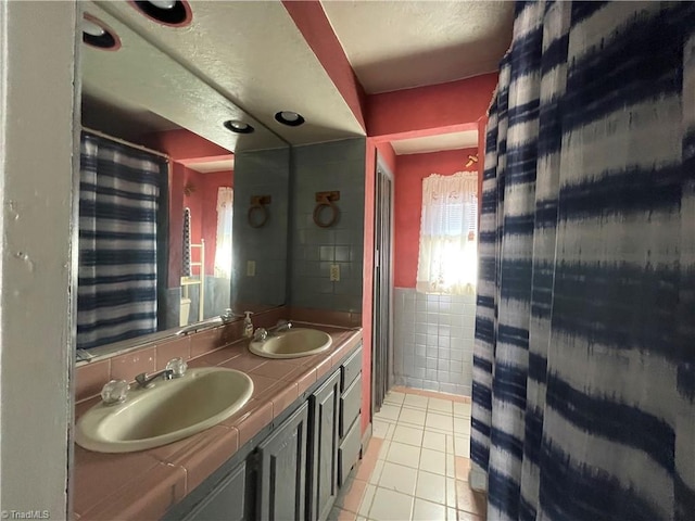 bathroom featuring tile patterned flooring, a sink, tile walls, and double vanity