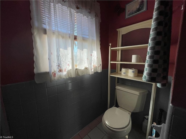 bathroom featuring toilet, tile patterned flooring, and tile walls