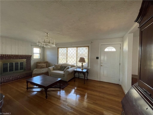 living room with a notable chandelier, a textured ceiling, a fireplace, and wood finished floors