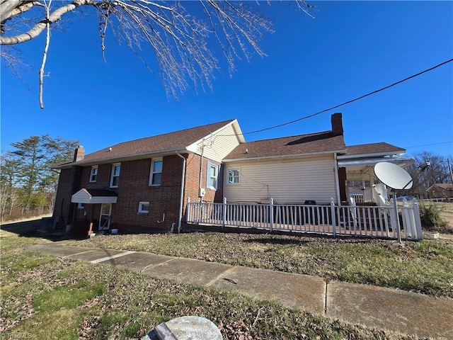 view of side of home featuring a chimney and brick siding