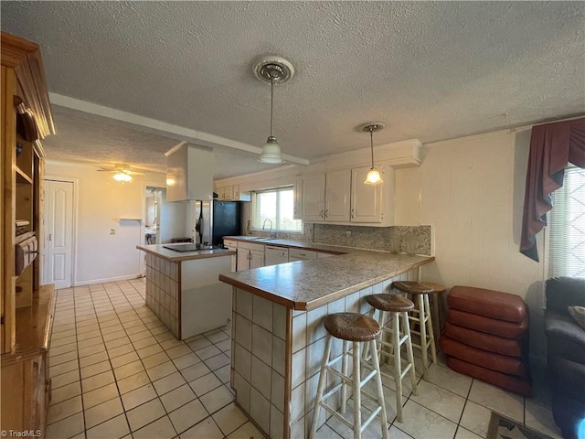 kitchen with white cabinets, a kitchen breakfast bar, a center island, a peninsula, and freestanding refrigerator