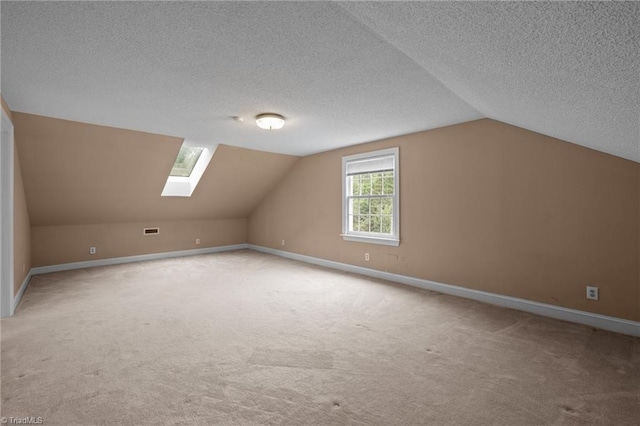 12088 Burlington Rd, Hurdle Mills, NC 27541 - additional living space with carpet flooring, vaulted ceiling, a skylight, baseboards, and a textured ceiling
