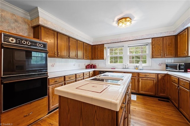 12088 Burlington Rd, Hurdle Mills, NC 27541 - kitchen with black appliances, tile countertops, brown cabinetry, light wood finished floors, and tasteful backsplash