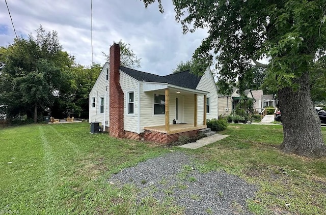 view of property exterior with central AC unit, roof with shingles, a porch, and a yard