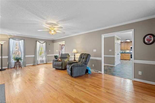 sitting room with visible vents, ornamental molding, a ceiling fan, a textured ceiling, and wood finished floors