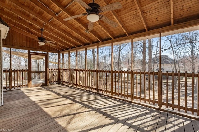 unfurnished sunroom featuring lofted ceiling, plenty of natural light, wood ceiling, and a ceiling fan