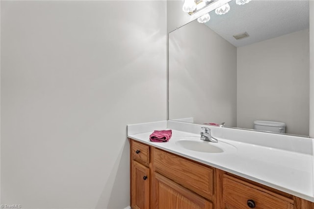 bathroom with visible vents, a textured ceiling, toilet, and vanity