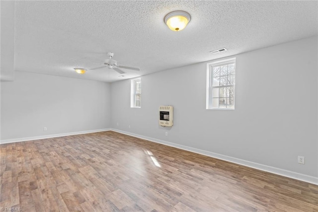 below grade area with heating unit, wood finished floors, baseboards, and ceiling fan