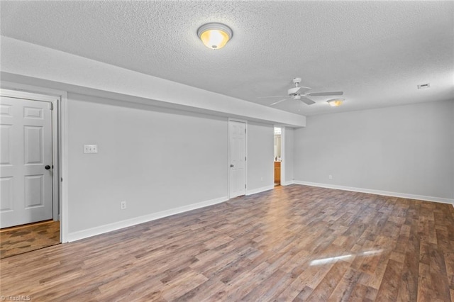 spare room featuring visible vents, baseboards, wood finished floors, a textured ceiling, and a ceiling fan