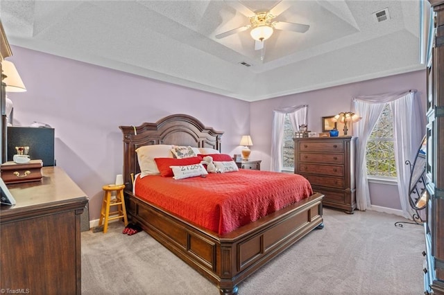 bedroom featuring baseboards, visible vents, a tray ceiling, a textured ceiling, and light carpet