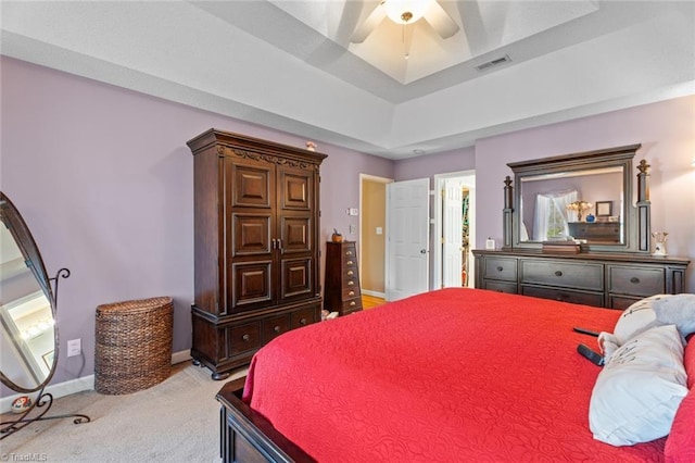 bedroom with a ceiling fan, visible vents, baseboards, a raised ceiling, and light colored carpet