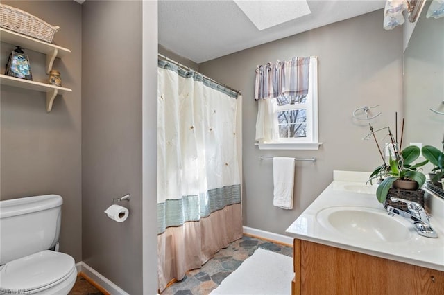 full bath featuring baseboards, toilet, a shower with shower curtain, a skylight, and a sink