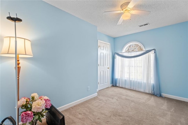 interior space featuring carpet, baseboards, visible vents, ceiling fan, and a textured ceiling