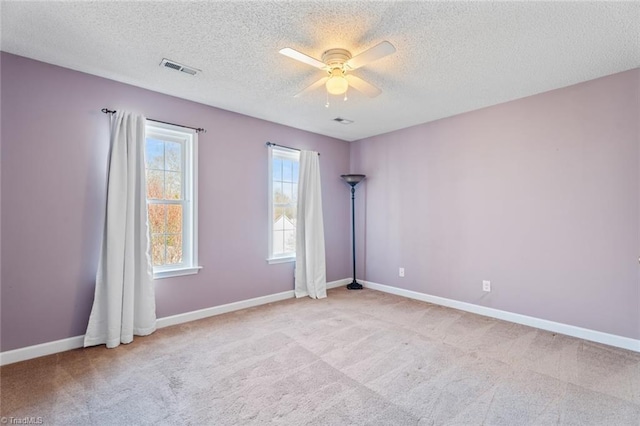 unfurnished room with visible vents, light carpet, a ceiling fan, a textured ceiling, and baseboards