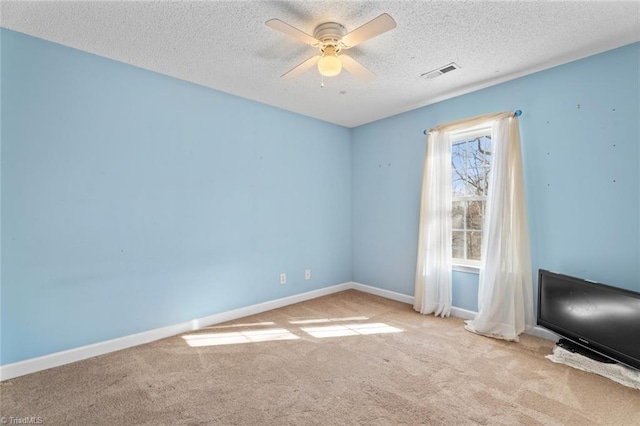 carpeted spare room featuring visible vents, baseboards, a textured ceiling, and ceiling fan