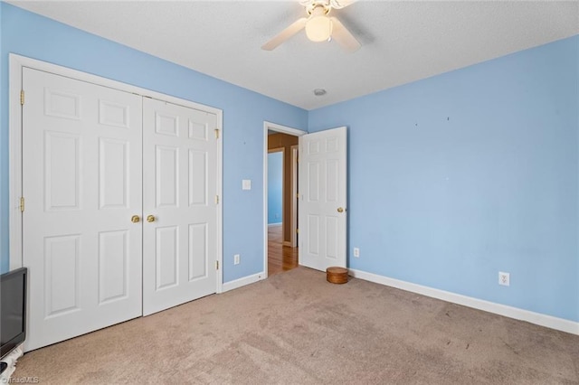 unfurnished bedroom featuring baseboards, carpet flooring, a closet, a textured ceiling, and a ceiling fan