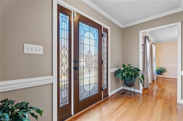 foyer entrance with a textured ceiling, light wood-style floors, and ornamental molding