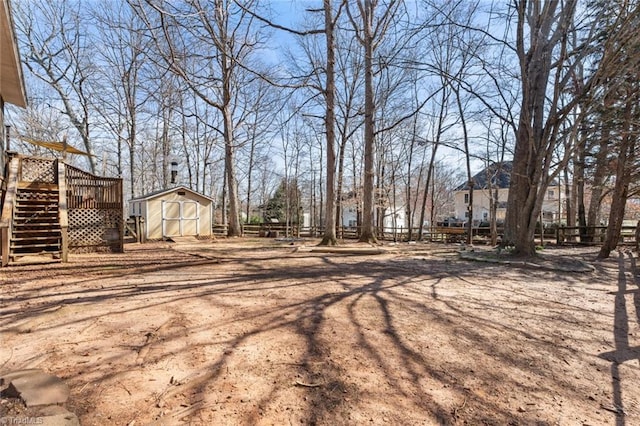 view of yard featuring an outbuilding, stairway, fence, a shed, and a wooden deck