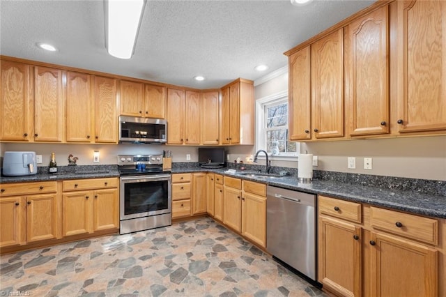 kitchen with a sink, dark stone countertops, a textured ceiling, and stainless steel appliances