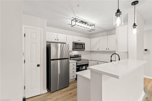 kitchen with pendant lighting, white cabinetry, light hardwood / wood-style floors, kitchen peninsula, and stainless steel appliances