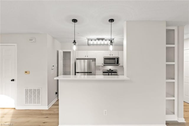 kitchen featuring white cabinetry, light hardwood / wood-style flooring, kitchen peninsula, pendant lighting, and stainless steel appliances