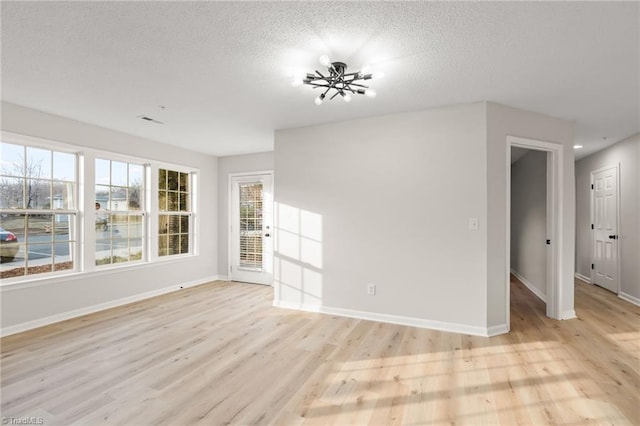 spare room with a textured ceiling and light wood-type flooring