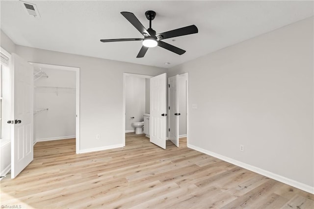 unfurnished bedroom with ceiling fan, a spacious closet, light wood-type flooring, and a closet