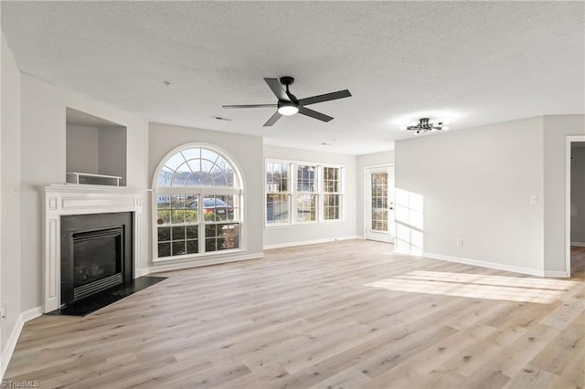 unfurnished living room featuring ceiling fan, a textured ceiling, and light hardwood / wood-style flooring