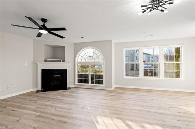 unfurnished living room with a textured ceiling, light hardwood / wood-style flooring, and a healthy amount of sunlight