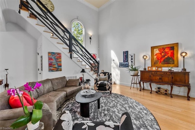 living area featuring crown molding, wood finished floors, stairway, and a towering ceiling