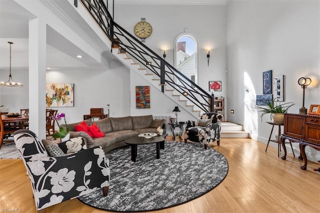 living area with stairs, a towering ceiling, wood finished floors, and a chandelier