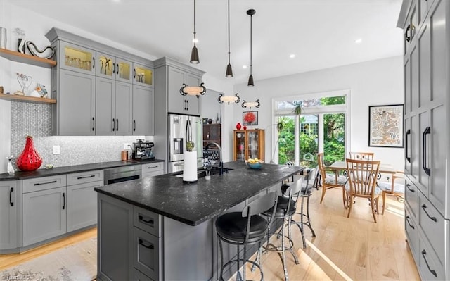 kitchen with light wood-style floors, a kitchen bar, stainless steel fridge with ice dispenser, a sink, and gray cabinetry