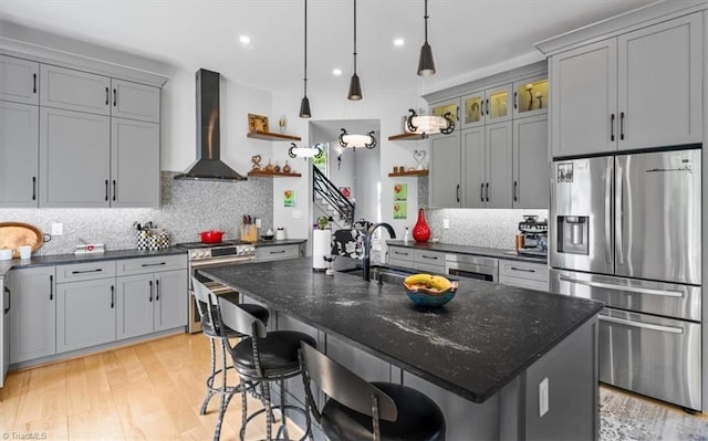 kitchen with open shelves, a sink, wall chimney exhaust hood, stainless steel appliances, and backsplash
