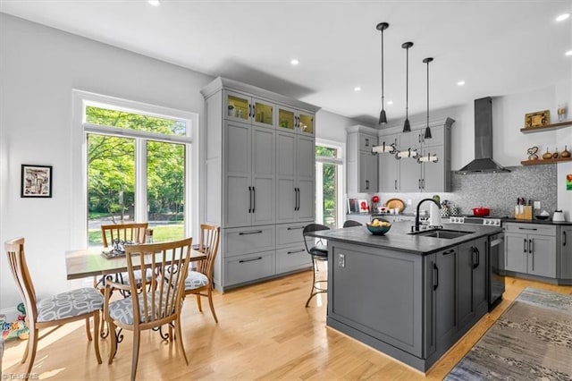 kitchen featuring wall chimney range hood, open shelves, a sink, gray cabinets, and backsplash