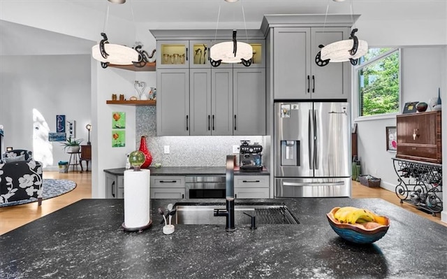 kitchen with open shelves, dark stone counters, stainless steel fridge with ice dispenser, backsplash, and hanging light fixtures