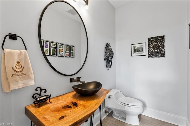 bathroom with baseboards, wood finished floors, toilet, and vanity