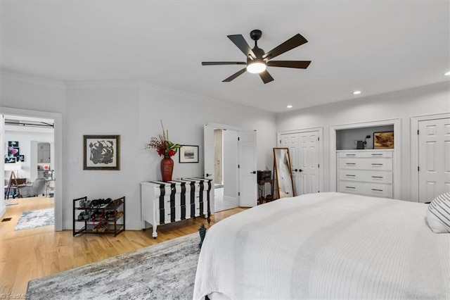 bedroom with baseboards, light wood finished floors, multiple closets, ornamental molding, and recessed lighting