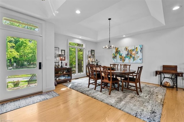dining area featuring a raised ceiling, recessed lighting, wood finished floors, and a notable chandelier