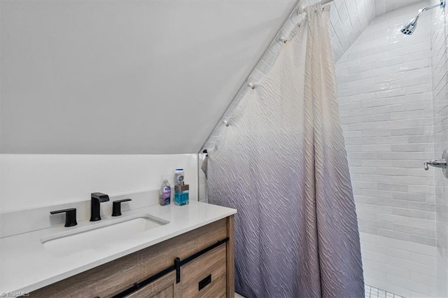 bathroom with vanity, vaulted ceiling, and tiled shower