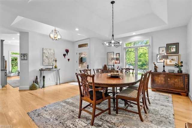 dining space with baseboards, a notable chandelier, light wood-style floors, a tray ceiling, and recessed lighting