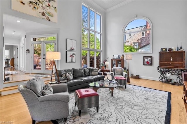living area featuring a high ceiling, ornamental molding, wood finished floors, and a healthy amount of sunlight