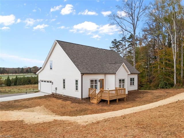 rear view of house featuring a garage and a wooden deck