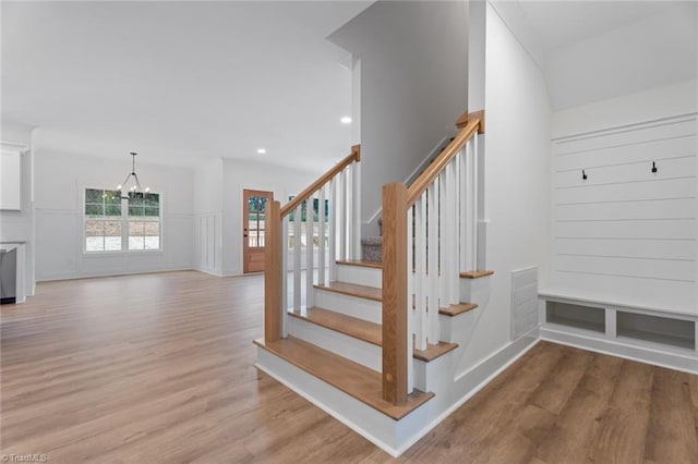 staircase with wood-type flooring and a chandelier