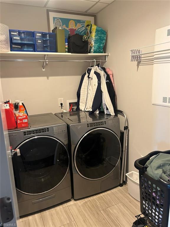 clothes washing area featuring laundry area, washing machine and dryer, and wood finished floors