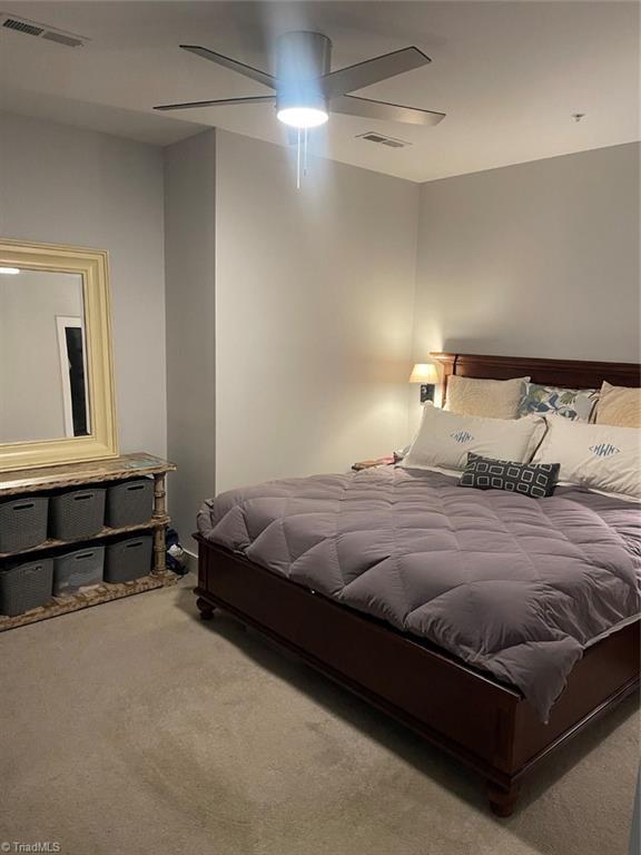 carpeted bedroom featuring visible vents and a ceiling fan