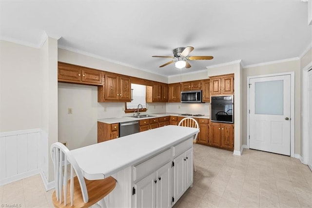 kitchen with light countertops, appliances with stainless steel finishes, a sink, and brown cabinets