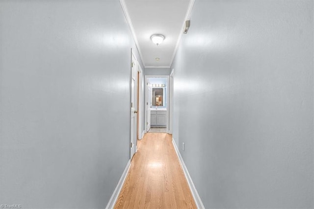 corridor featuring light wood-type flooring, baseboards, and crown molding