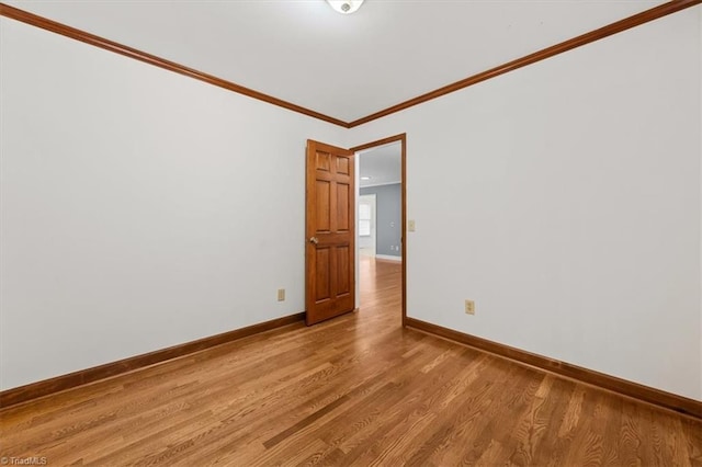 unfurnished room featuring baseboards, crown molding, and light wood-style floors