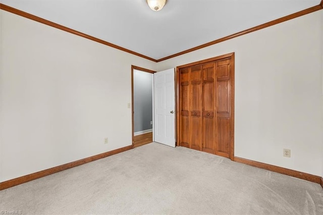 unfurnished bedroom featuring ornamental molding, carpet, a closet, and baseboards